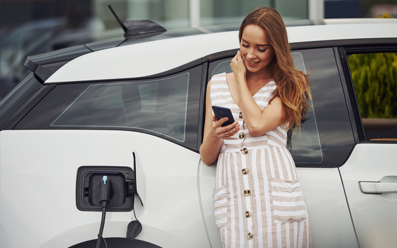 woman charging an EV with phone