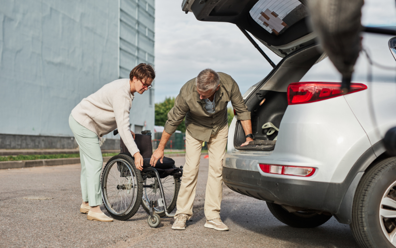 Couple preparing to load wheelchair into boot of car